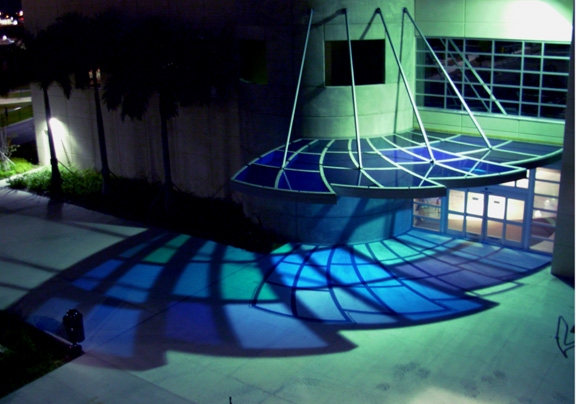 Flood lighting illuminates a glass canopy at the entrance of Broward Community College Library